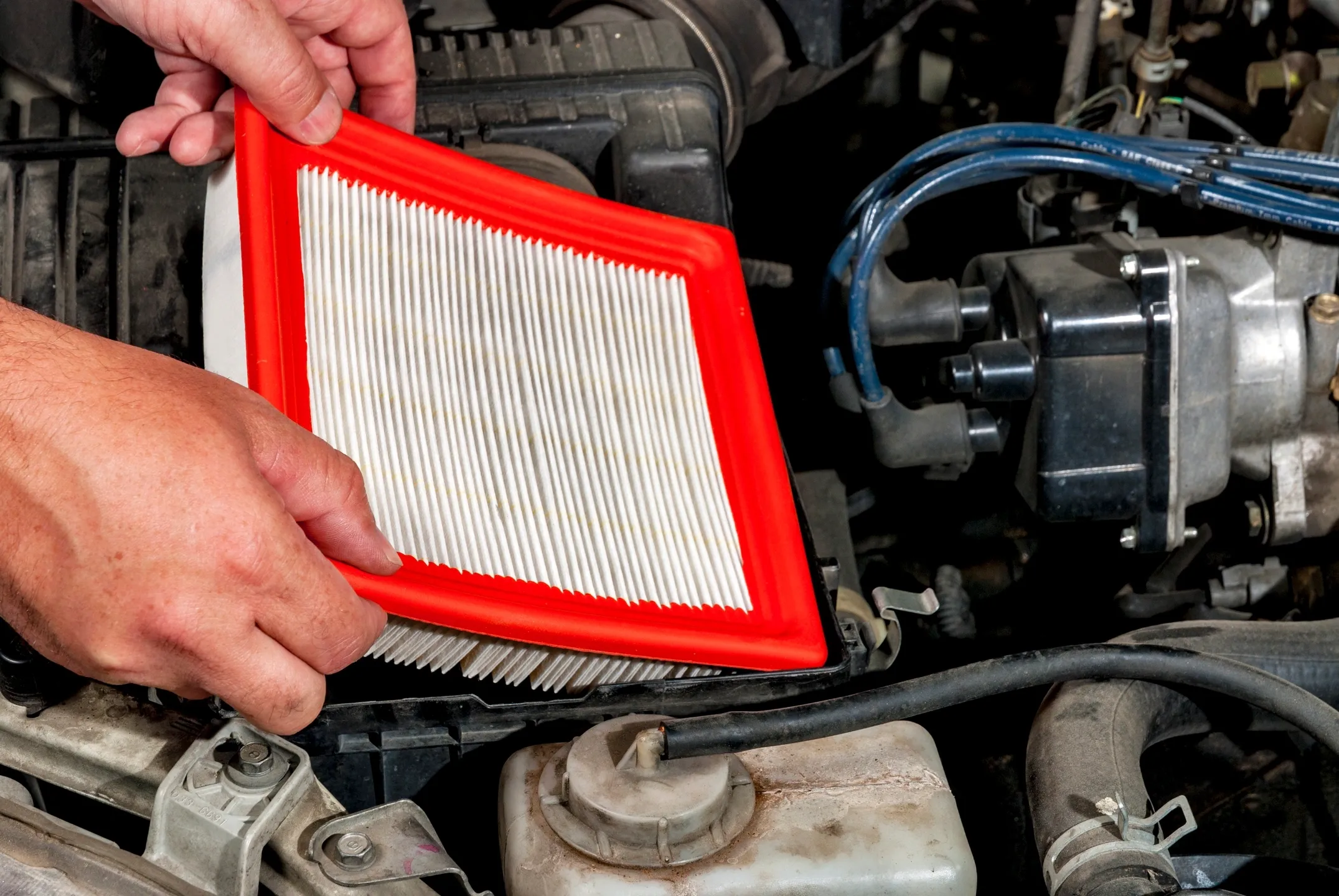 A person holding an air filter in front of the engine.